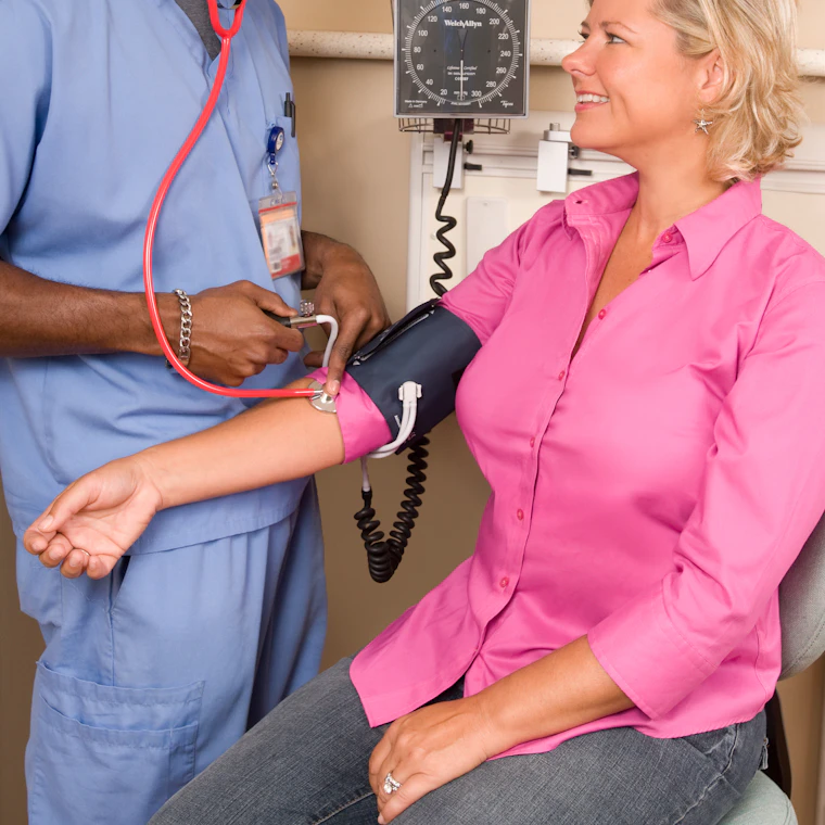 Healthcare worker checking a colleague's blood pressure during a health camp