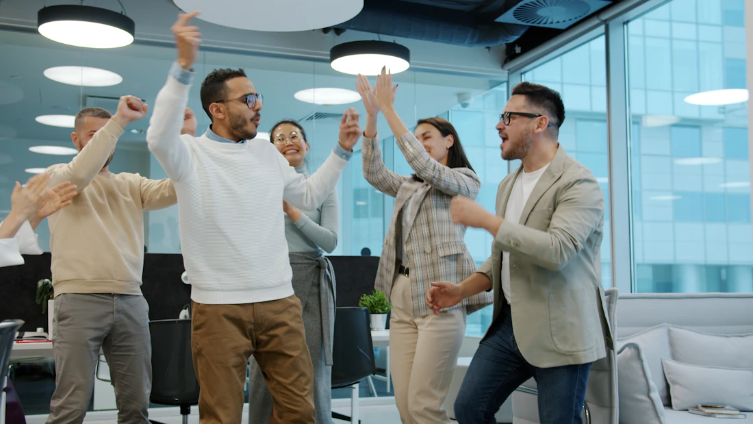 Diverse team celebrating and high-fiving in a modern office