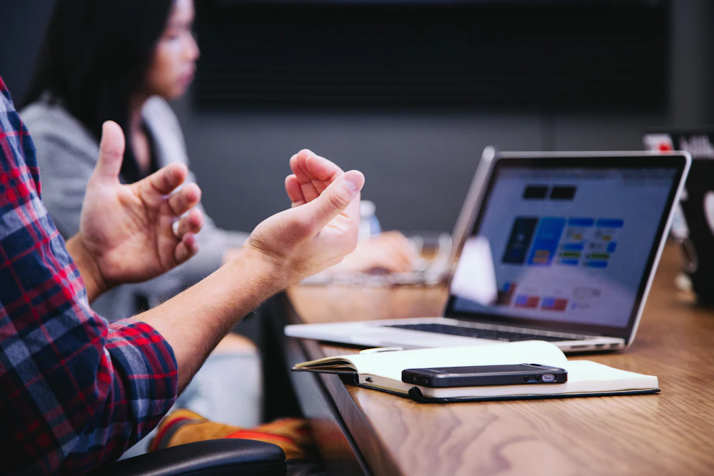 Colleague gesturing during a financial discussion with a laptop showing charts