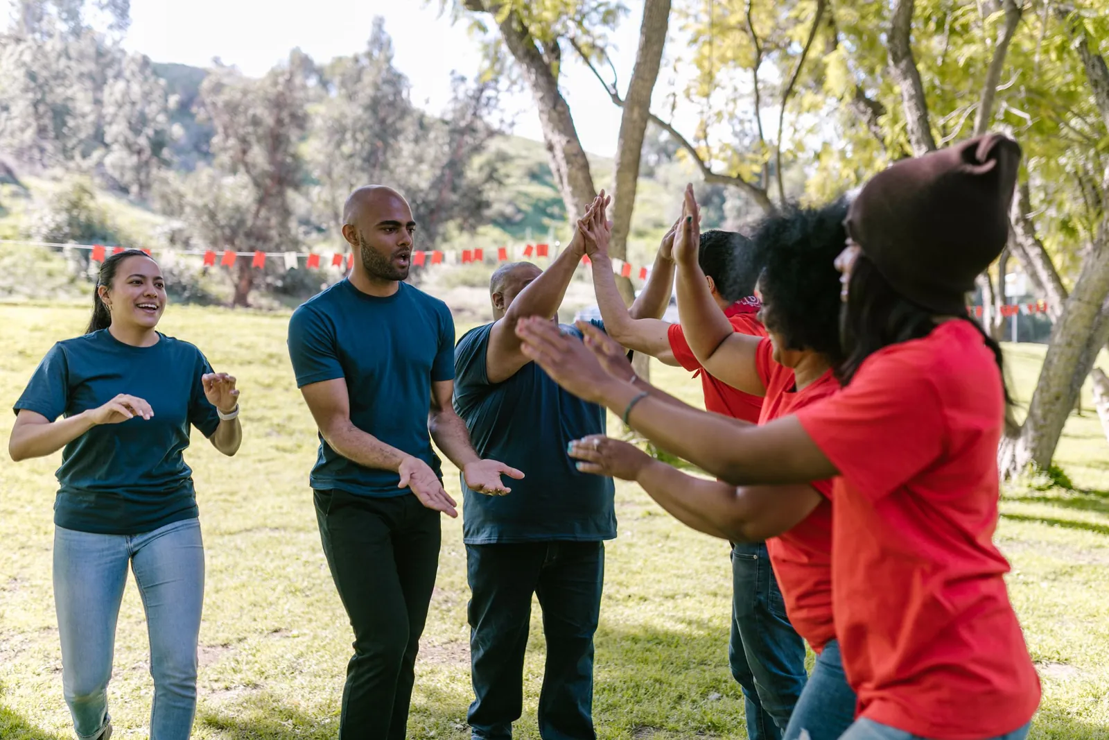 Corporate colleagues high-fiving and celebrating together during an outdoor team-building activity