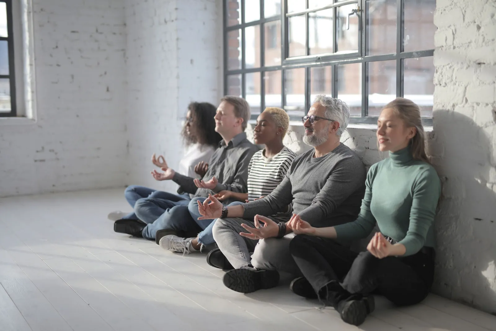 Diverse group of colleagues sitting together and practising mindful breathing during a workplace wellness session