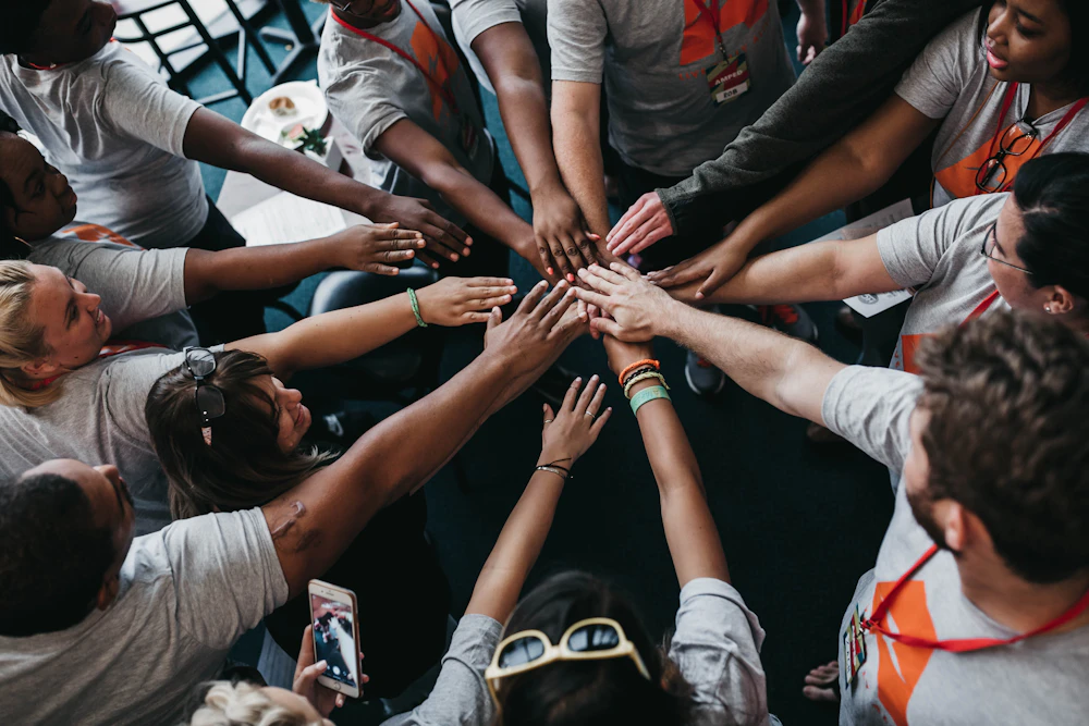 Colleagues gathered together in a circle, hands stacked during a team engagement activity