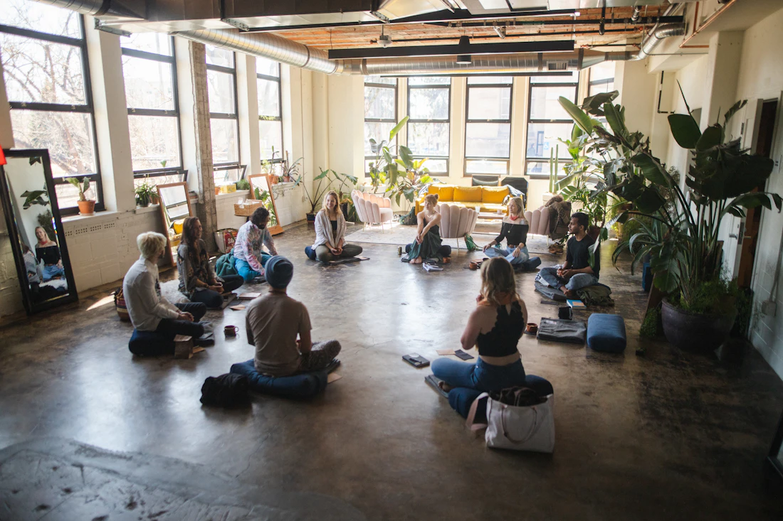 Employees sitting together in a bright office loft for a guided mindfulness and meditation session